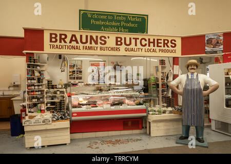 Un macellaio di stallo Brauns (famiglia tradizionale macellaio) nel mercato coperto nella città balneare di Tenby, Pembrokeshire, Galles Foto Stock