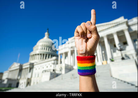 Mano che indossa il Gay Pride rainbow polsino tenendo alto il numero uno del dito indice al di fuori del Campidoglio di Washington, DC, Stati Uniti d'America Foto Stock