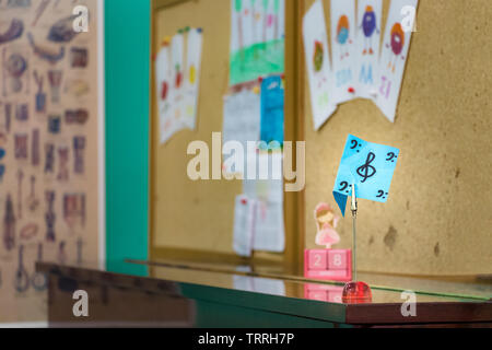 Una chiave di violino è scritta su una carta, posta sulla sommità di un pianoforte in una classe di musica. Foto Stock