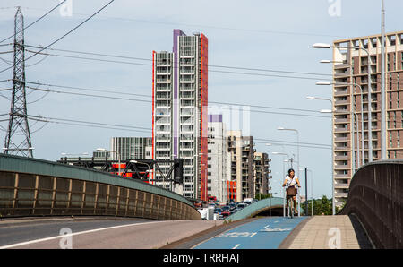 London, England, Regno Unito - 1 Giugno 2019: Un ciclista viaggia lungo il superhighway di ciclo 3 passato nuova build alta edifici di appartamenti in la Canning Town neighb Foto Stock