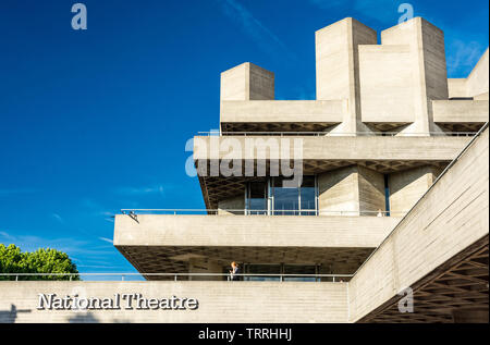 London, England, Regno Unito - 31 Maggio 2019: una donna cammina lungo una delle terrazze di cemento del brutalist Teatro Nazionale Building a Londra il South Bank Foto Stock