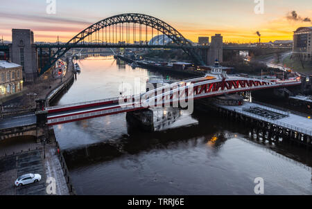 Newcastle, England, Regno Unito - 5 Febbraio 2019: Il sole sorge dietro l'iconica Tyne Bridge e ponte girevole tra Newcastle e Gateshead sul fiume T