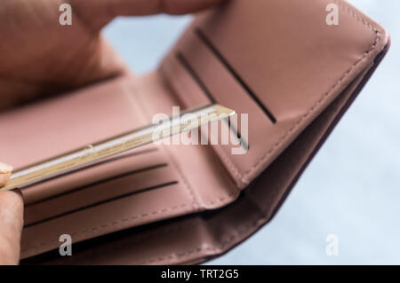 Primo piano del giovane imprenditore inserendo o estraendo o pagando con carta di credito in portafoglio in pelle su sfondo bianco. Messa a fuoco selettiva. Guadagnare cr Foto Stock