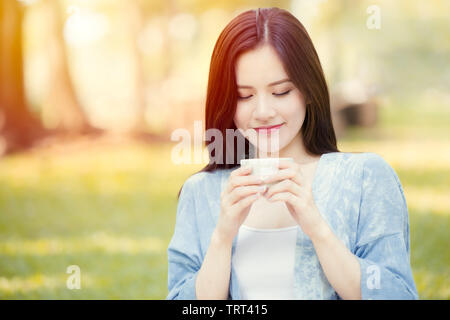 Girl Teen tenendo la tazza per bere il tè caldo nel parco mattina sorriso Foto Stock