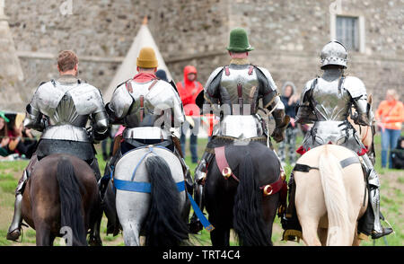 Vista posteriore di quattro cavalieri, dimostrando la loro equitazione abilità, durante un patrimonio Inglese giostre del torneo al castello di Dover, Agosto 201 Foto Stock