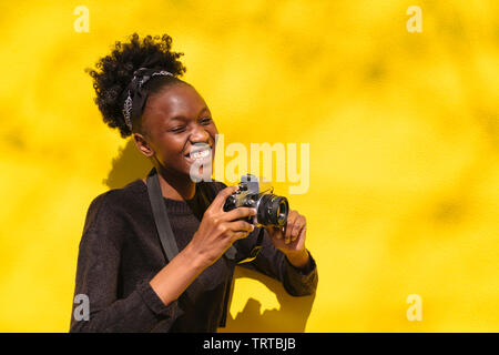 Felice giovane americano africano fotografo femmina con la fotocamera in estate street Foto Stock