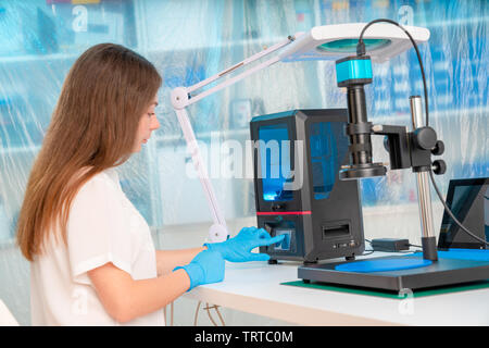 Lavoratore di sesso femminile nel controllo di resina LCD / DLP / SLA stampante 3D nel laboratorio di tecnologia Foto Stock