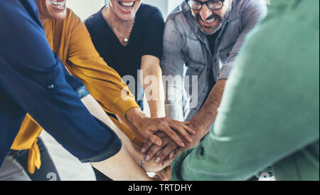 Multi-etnico business persone mettere le mani sulla parte superiore di ogni altro. Il team di Business facendo una pila di mani che mostra l'unità. Foto Stock