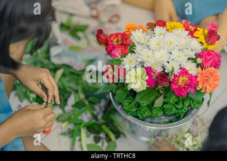 Gli studenti si aiutano a vicenda per creare un vassoio di fiori con il piedistallo per gli Insegnanti" Giorno Foto Stock