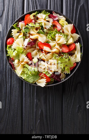 Deliziosi piatti di pasta italiana con insalata di avocado, le fragole, le lattughe, conditi con salsa balsamica di close-up su una piastra sul tavolo. Verticale in alto visualizza fro Foto Stock