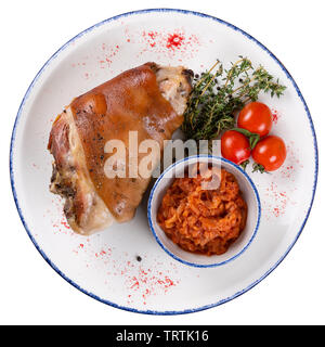 Fuso a snodo di maiale con pomodori e crauti su un round piastra di luce con un bordo blu su bianco sfondo isolato, vista dall'alto. Foto Stock