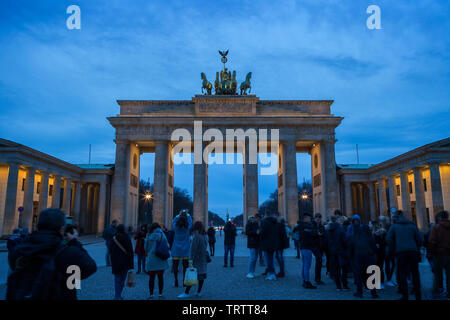 Molti turisti scattare foto e appendere fuori al famoso e neoclassico illuminato Porta di Brandeburgo (Brandenburger Tor) di Berlino in Germania al crepuscolo Foto Stock