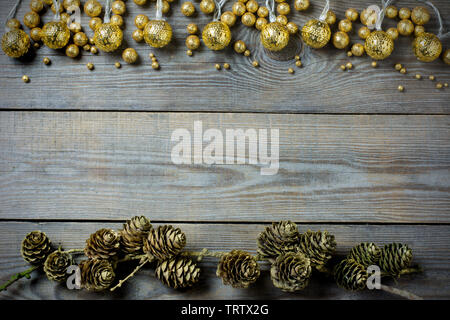 Composizione di natale con coni d'oro, globuli di glitter e golden luci fairy su sfondo di legno - Spazio di testo Foto Stock