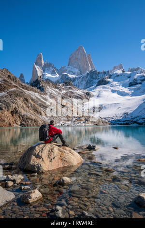 Walker sat ammirando la vista del monte Fitz Roy e Cerro Torre con Lago de los Tres, El Chalten, Patagonia, Argentina. Foto Stock