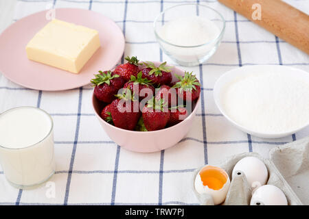 Torta alle fragole ingredienti (farina, uova, burro, latte, zucchero, fragola), vista laterale. La cottura di torta alle fragole o torta. Sfondo di cibo. Foto Stock
