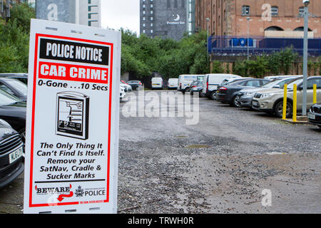 Una macchina della polizia la criminalità un cartello di segnalazione sull ingresso del parco auto in Manchester City Centre Foto Stock