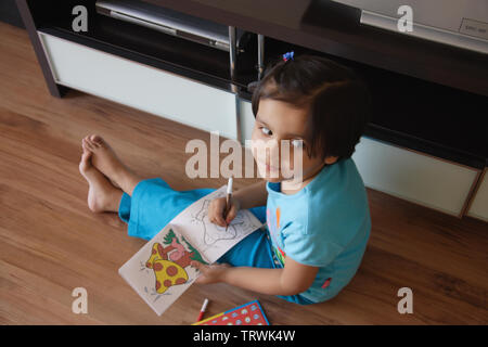 Elevato angolo di visione di una ragazza di colorazione in un libro Foto Stock