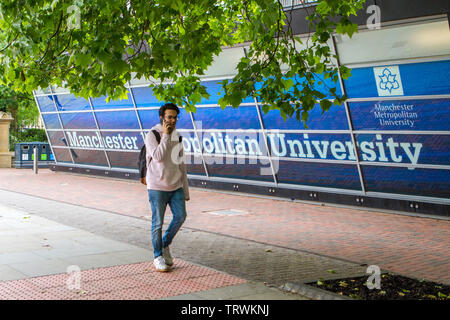 Un maschio di studente passeggiate passato la Manchester Metropolitan University segno di Oxford Road, Manchester, Regno Unito Foto Stock