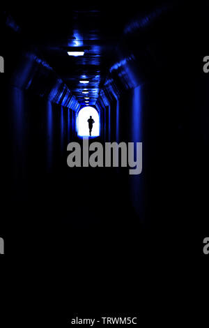 Uomo che corre nel tunnel verso la luce alla ricerca di una certa destinazione e il conseguimento degli obiettivi Foto Stock