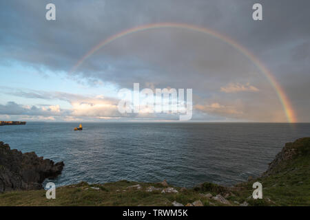 Ampia oasi in una serata estiva con un arcobaleno sul mare e chiesa Rock, Pembrokeshire Coast, Wales, Regno Unito Foto Stock
