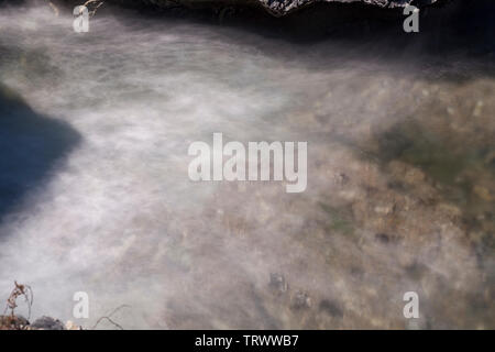 Sullo sfondo del mare visto attraverso l'acqua di mare con onde di schiuma di trascinamento sulla sua superficie. Ideale per uso come sfondo. Foto Stock