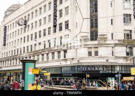 Le persone camminano davanti al negozio Debenhams (l'edificio Rylands) & Market Street fermata del tram, Manchester, Inghilterra, Regno Unito Foto Stock