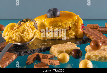 Delizioso pezzo di torta circondata da caramelle e barrette di cioccolato al di sopra di un tavolo di vetro Foto Stock