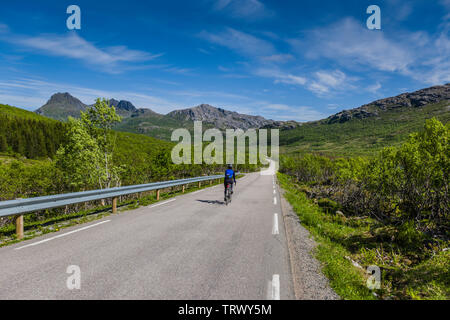 Femmina ciclista su strada a Nusfjord, Isole Lofoten in Norvegia. Foto Stock