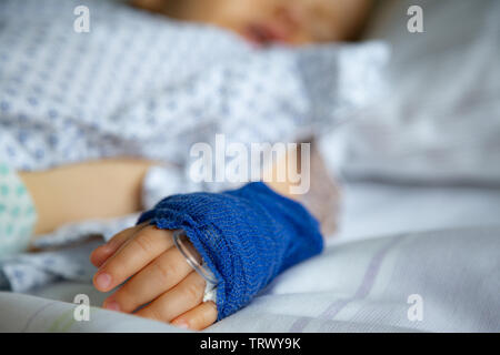 Dormire bambino malato con periferiche linea venosa sulla sua mano sinistra in ospedale Foto Stock
