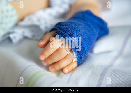 Dormire bambino malato con periferiche linea venosa sulla sua mano sinistra in ospedale Foto Stock