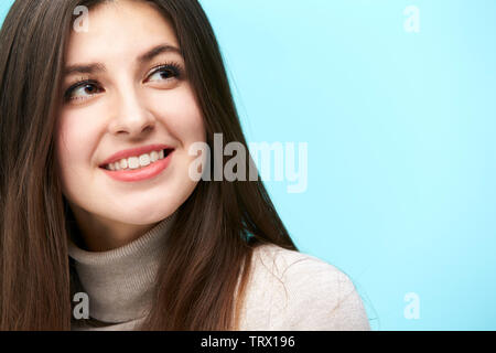 Testa e la spalla ritratto di una giovane donna caucasica isolata su sfondo blu Foto Stock