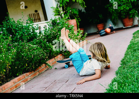 5 anno vecchio ragazzo la pratica di skate nel suo cortile, inciampare e cadere a terra. Foto Stock