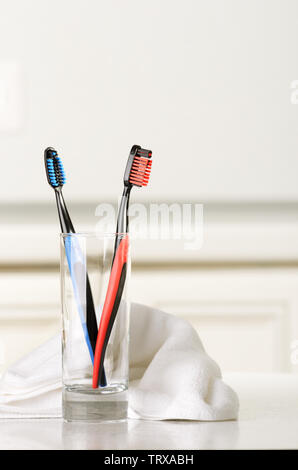 Gli spazzolini da denti in un bicchiere e la salvietta sul tavolo. Messa a fuoco selettiva. Foto Stock