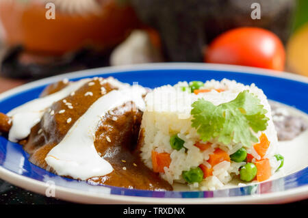 Mole messicano salsa con pollo, riso e nero refried fagioli. Servito oltre alla tradizionale pentola di creta per la cottura dei fagioli. Cibo tradizionale da Oaxaca a Foto Stock