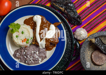 Mole messicano salsa con pollo, riso e nero refried fagioli. Servita al fianco di ingredienti come il cioccolato e peperoncino. Cibo tradizionale da Oaxaca a Foto Stock