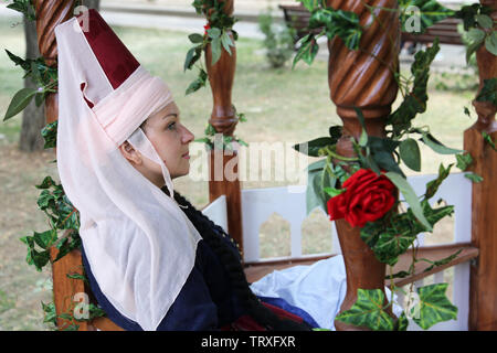 Donna che indossa abiti tradizionali dell'Impero Ottomano seduta seduta in un gazebo coperto con fiori durante la mosca festival storici Foto Stock