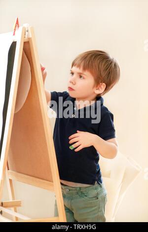 Il bambino è il disegno e la pittura con il pennarello su carta del disegno di legno artista scheda cavalletto per ragazzi e bambini a casa. Infanzia. Carino piccolo ragazzo. Foto Stock