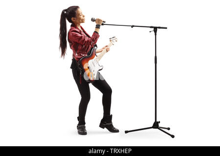 A piena lunghezza shot di una femmina di musicista rock con una chitarra cantando su un microfono isolati su sfondo bianco Foto Stock