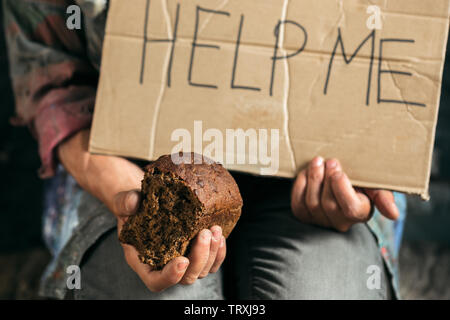 Mendicante maschio le mani in cerca di denaro con segno HELP ME da gentilezza umana su pavimento di legno alla pubblica strada o lungo la strada pedonale. Senzatetto poveri della città. Problemi con la finanza, luogo di residenza. Foto Stock