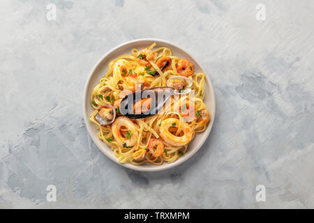 Piatti di pasta. Un piatto di tagliolini con cozze, gamberi, vongole e anelli di calamari, girato dalla parte superiore con spazio di copia Foto Stock