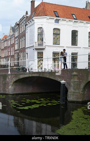 Giovani in amore matura abbracciando e baciando permanente sulla cima di un ponte nel centro della città Foto Stock