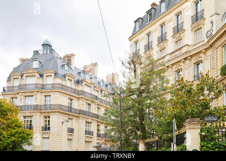 Parigi, Francia - 22 luglio 2017: antichi edifici di lusso facciata con alberi e ringhiere con golden punti in una giornata nuvolosa a Parigi, Francia Foto Stock