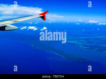 Vista aerea da aereo. Una prospettiva aerea di terra e il blu Oceano su un pulito cielo blu giornata con aereo ala. Foto Stock