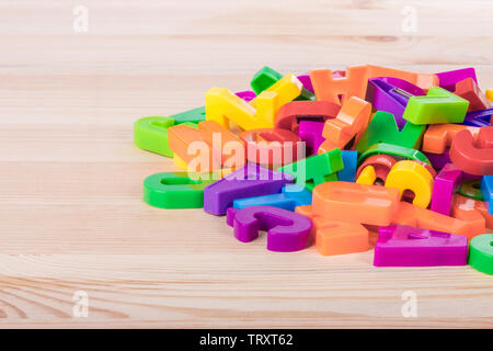 Un mucchio di colorate le lettere magnetiche su una scuola tavolo in legno Foto Stock