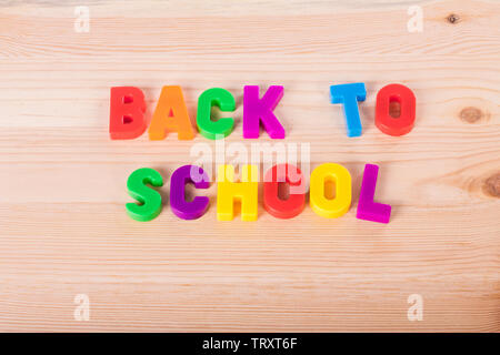 Si torna a scuola il testo scritto con colorato magnetico lettere al di sopra di una scuola in legno tabella Foto Stock