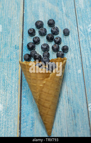 Berry stagione. Berry ice cream. Bacche di mirtilli in un disegno waffle su un blu sullo sfondo di legno Foto Stock