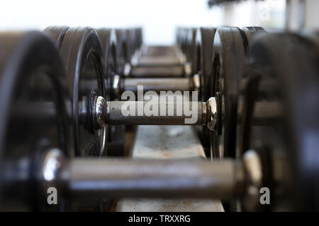 Pesante metallo nero manubri giacente in una fila, primo piano Foto Stock
