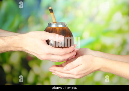 Man mano dando calabash e bombilla con yerba mate, su sfondo natura Foto Stock