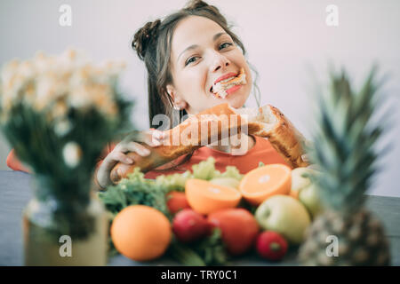 Giovane donna su una dieta ceduto alla tentazione e appassionatamente morde un bianco lungo croccante pane. Il concetto di dieta, mangiare sano e di rigetto di ba Foto Stock