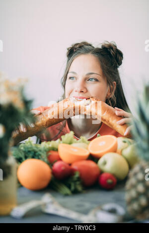 Giovane donna su una dieta ceduto alla tentazione e appassionatamente morde un bianco lungo croccante pane. Il concetto di dieta, mangiare sano e di rigetto di ba Foto Stock